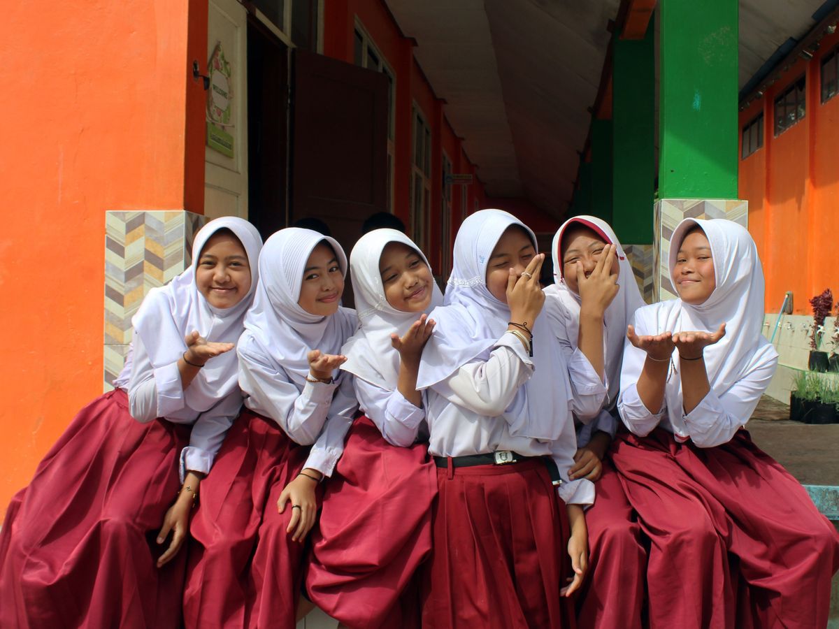 Sekelompok siswi Indonesia tersenyum bersama di lingkungan sekolah